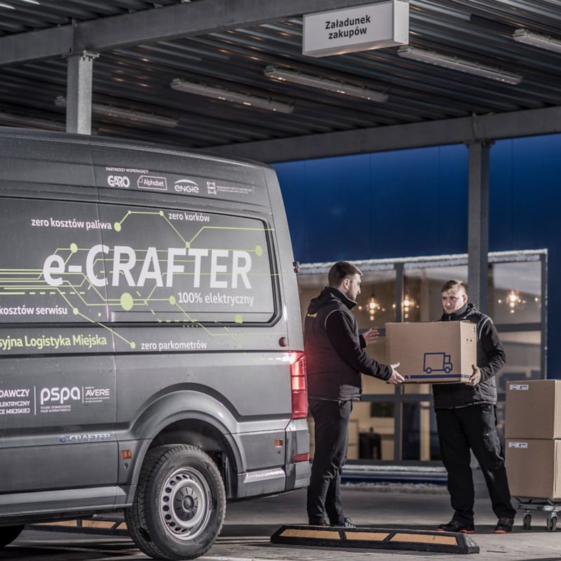 Kurierzy pakują paczki do Craftera oklejonego w logo Misja Zerowa Emisja