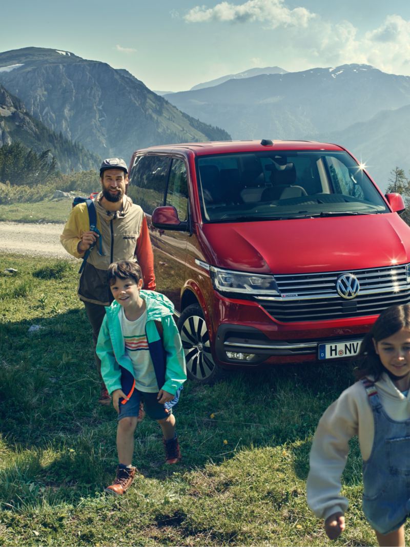 En röd VW Multivan minibuss med en familj