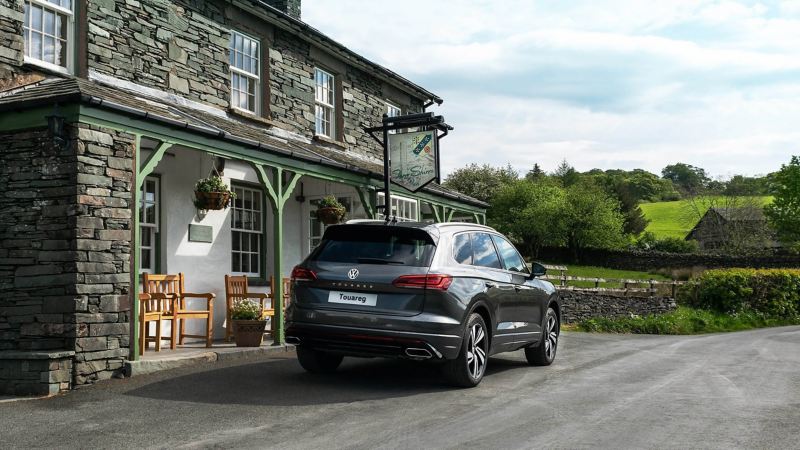 A silver Volkswagen Touareg parked near a cottage