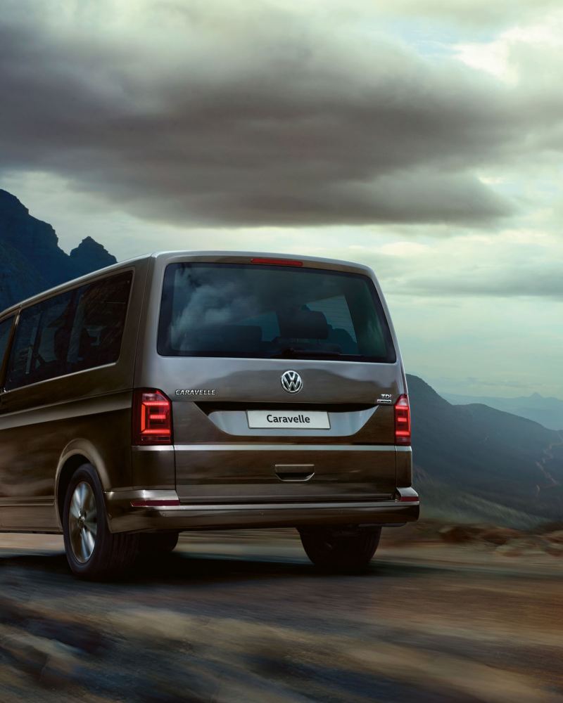 A Volkswagen van for families, the Caravelle driving away into the mountains on an overcast day.