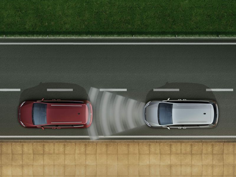 A silver Volkswagen Sharan driving behind a red Volkswagen Sharan with sound waves that represent the Front Assist