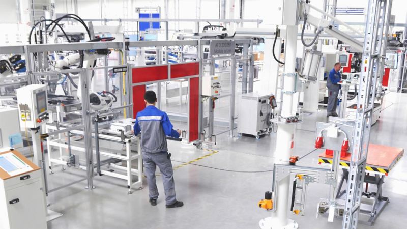 Two Volkswagen employees at their workstations on the factory floor