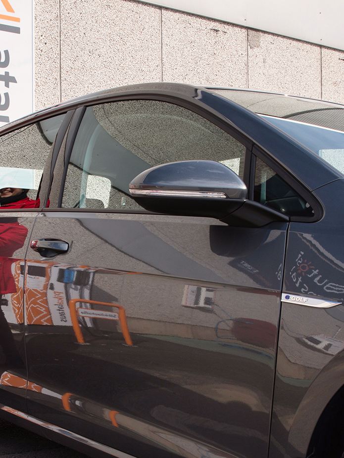 Kuva henkilöstä lataamassa Volkswagenin sähköautoa latauspisteellä