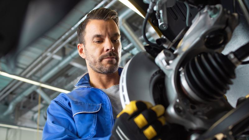 A VW technician wearing a glove with hand on a tyre