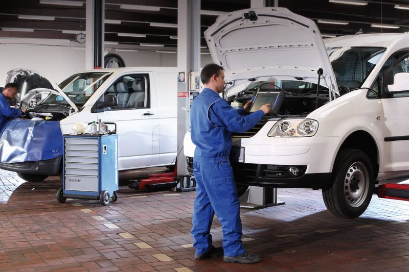 Volkswagen van specialist using diagnostic equipment under hood of van