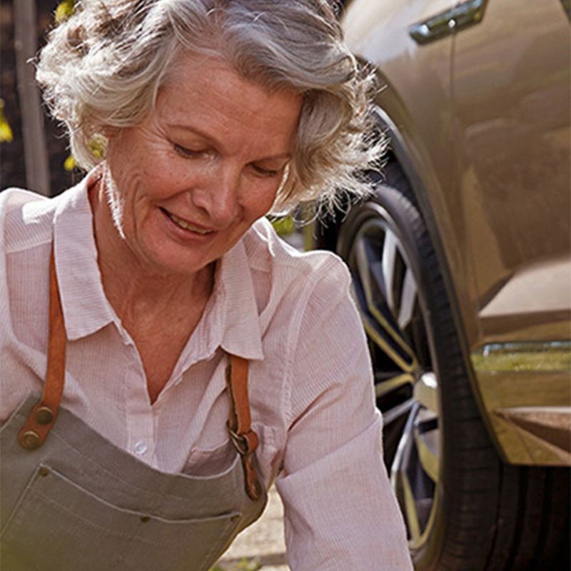Ältere Frau im Garten vor Fahrzeug – Leasing-Angebote