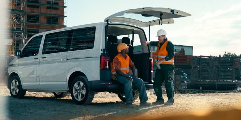 The Volkswagen Transporter 6.1 Kombi is standing on a construction site, two workers are on their break.