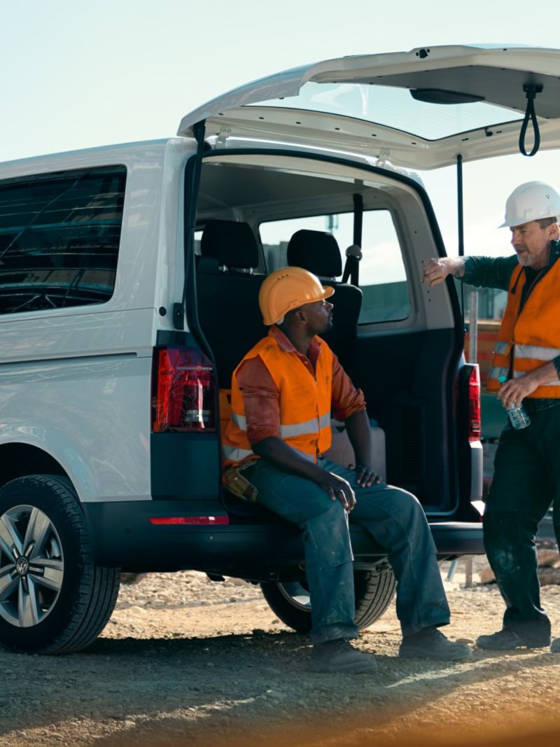 The Volkswagen Transporter 6.1 Kombi is standing on a construction site, two workers are on their break.