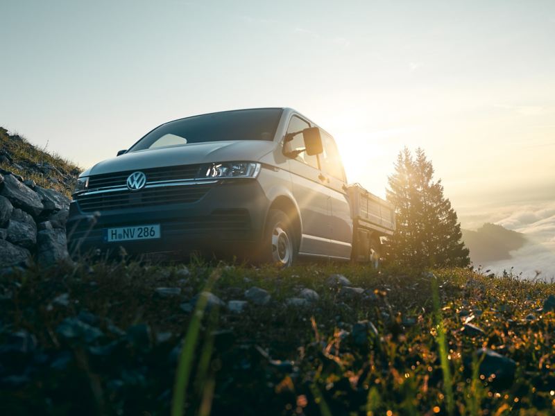 Le Transporter 6.1 à plateau est sur une montagne au-dessus des nuages.
