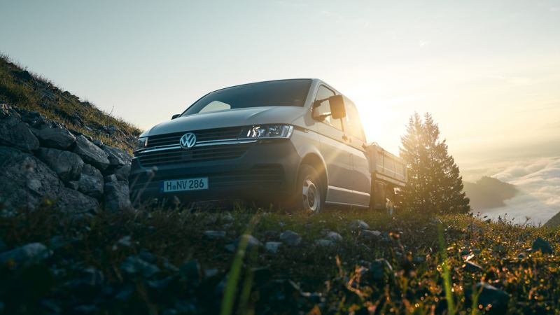 Le Transporter 6.1 à plateau est sur une montagne au-dessus des nuages.