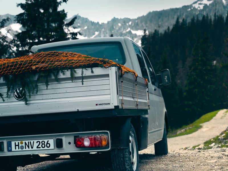 vw Volkswagen Transporter pickup kjører i skråning med fjell i bakgrunn lasteplan