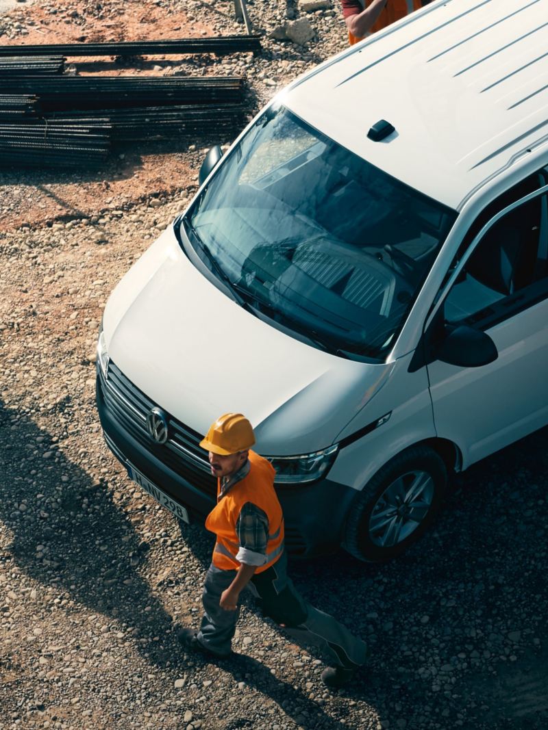 Einige Bauarbeiter stehen auf einer Baustelle um ihren Volkswagen Transporter 6.1 Kombi.