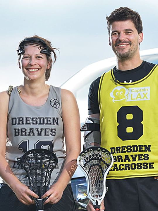Zwei Lacrosse-Spieler stehen vor einem Volkswagen Nutzfahrzeuge Transporter.