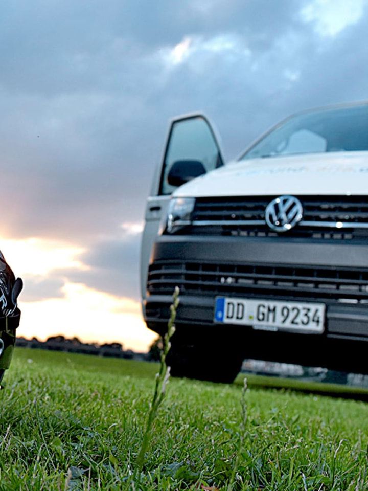 Ein Volkswagen Nutzfahrzeuge Transporter steht auf einem Lacrosse-Feld. Im Vordergrund ist ein Lacrosse-Helm zu sehen.