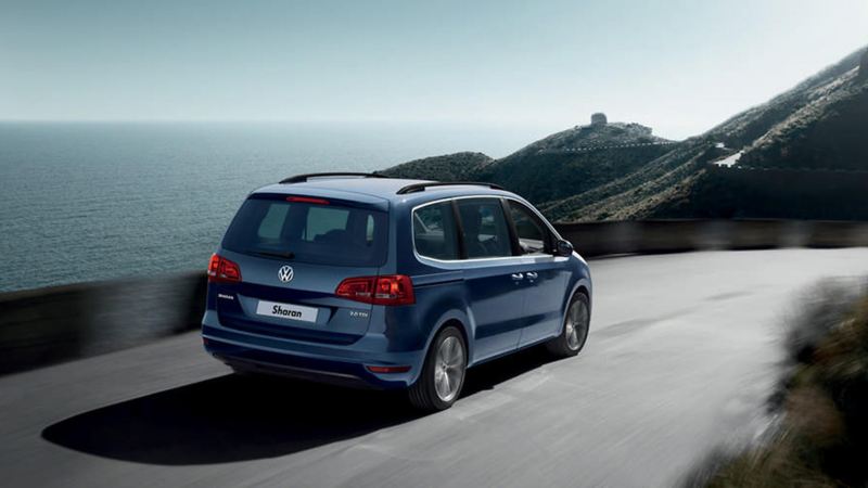 Blue Volkswagen Sharan, driving on a mountainous costal road. 