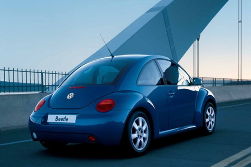 Rear view of a blue Volkswagen Bettle, crossing a suspension bridge.