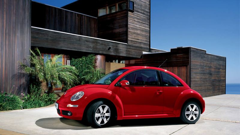 A red Volkswagen Beetle parked in front of  house