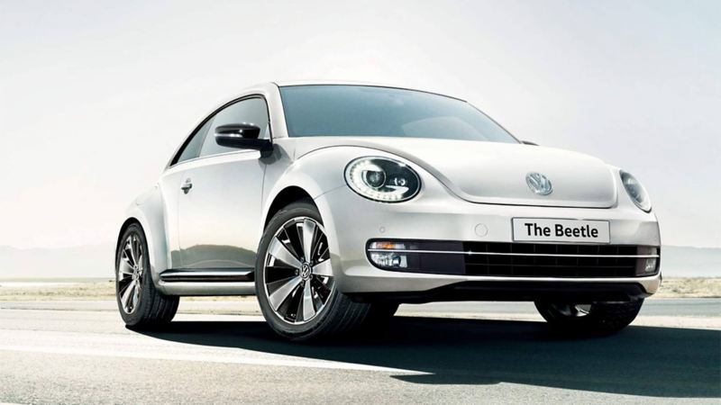 Front view of a white Volkswagen Beetle, on a desert. road