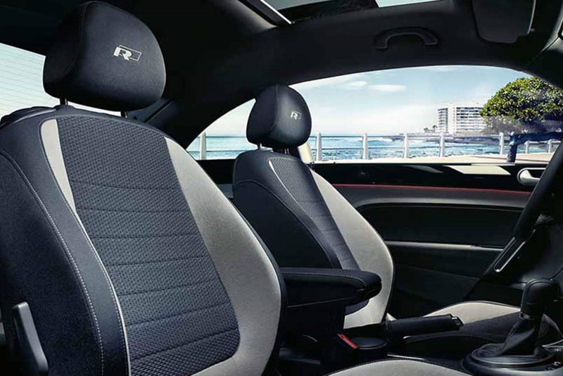 Interior shot of a Volkswagen Beetle, with the sea in the background.