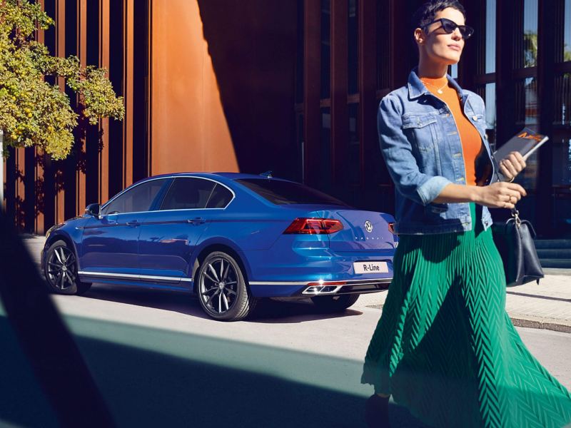 A lady walking past a blue VW Passat
