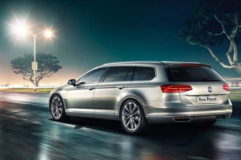 Rear shot of a silver Volkswagen Passat Estate, driving on a wet road.