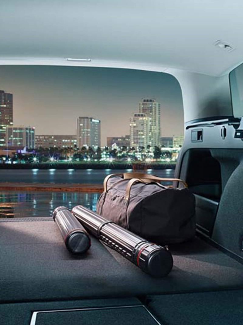 Interior shot of a Volkswagen Passat Estate , seats down, boot open and a night time city skyline in the distance.