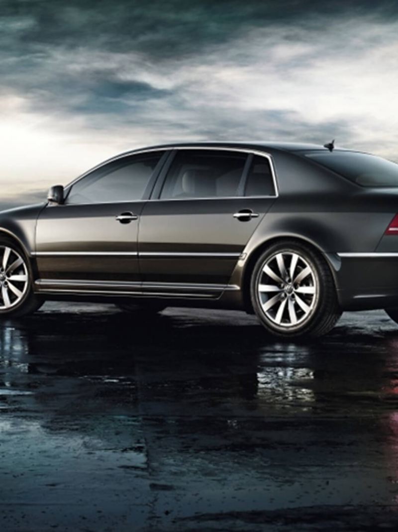 Profile shot of a grey Volkswagen Phaeton, on a wet beach, the tide out.