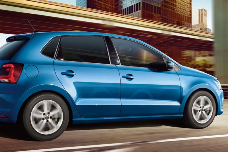 Profile shot of a blue Volkswagen Polo, driving through a city.