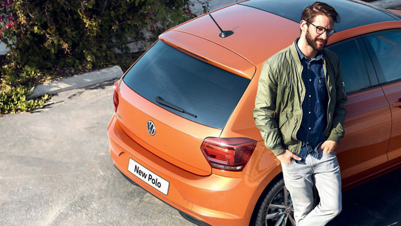 Man leaning on the side of a orange Polo.