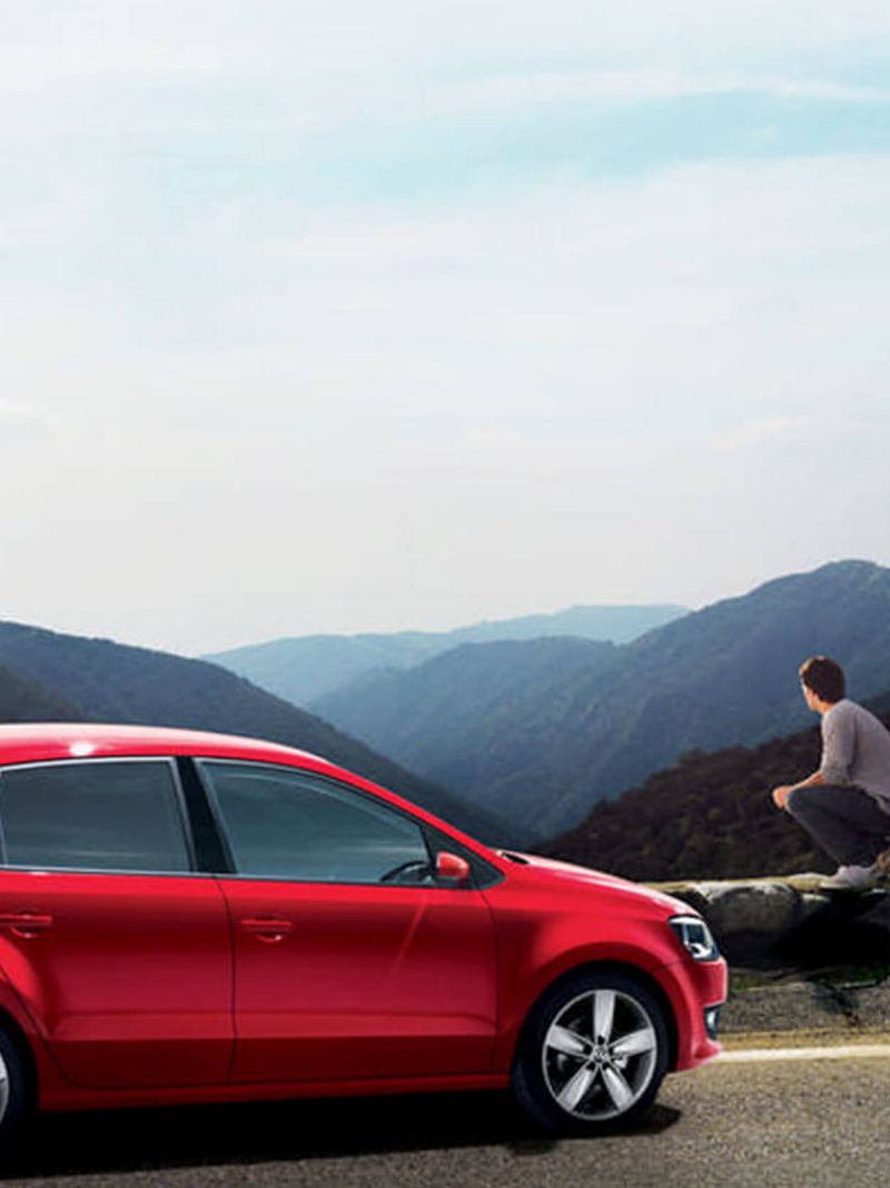 Red Volkswagen Polo, parked at the side of a mountain road.