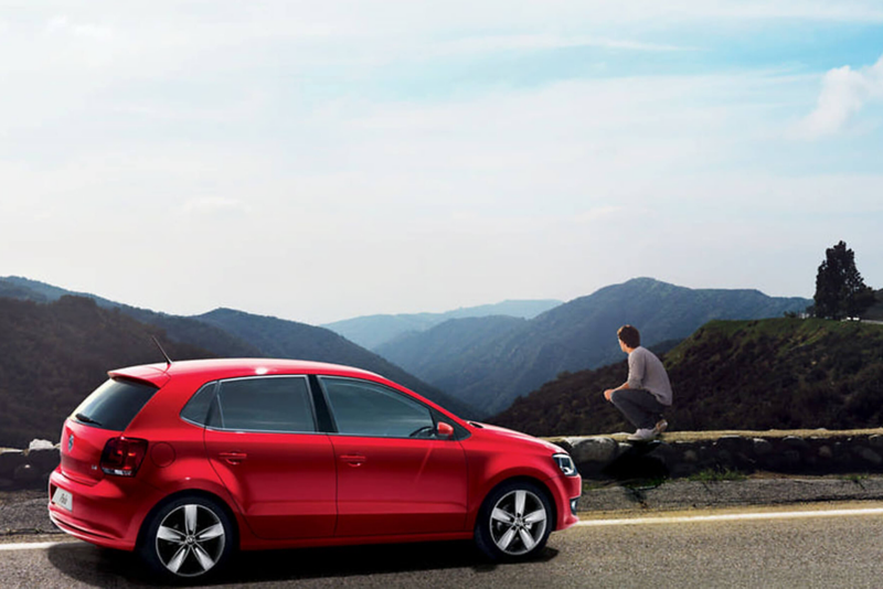 Red Volkswagen Polo, parked at the side of a mountain road.