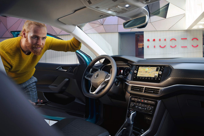 Man looking through the drivers door, at the interior of a Volkswagen T-Cross.