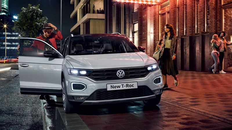 A man and woman getting into a white Volkswagen T-Roc.