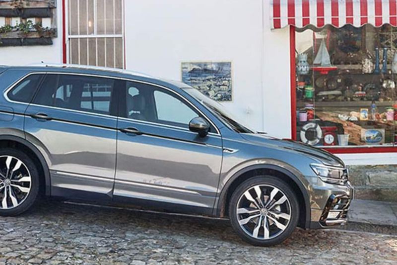Grey Volkswagen Tiguan, on a slopping cobble street.