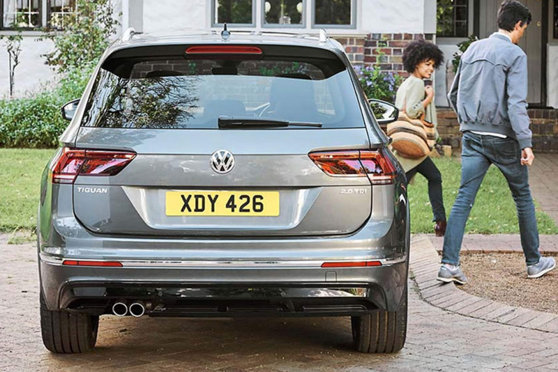 Rear shot of a grey Volkswagen Tiguan, parked as a couple walk away.