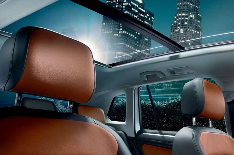 Interior shot of a Volkswagen Tiguan seats and sunroof, skyscrapers in the background.