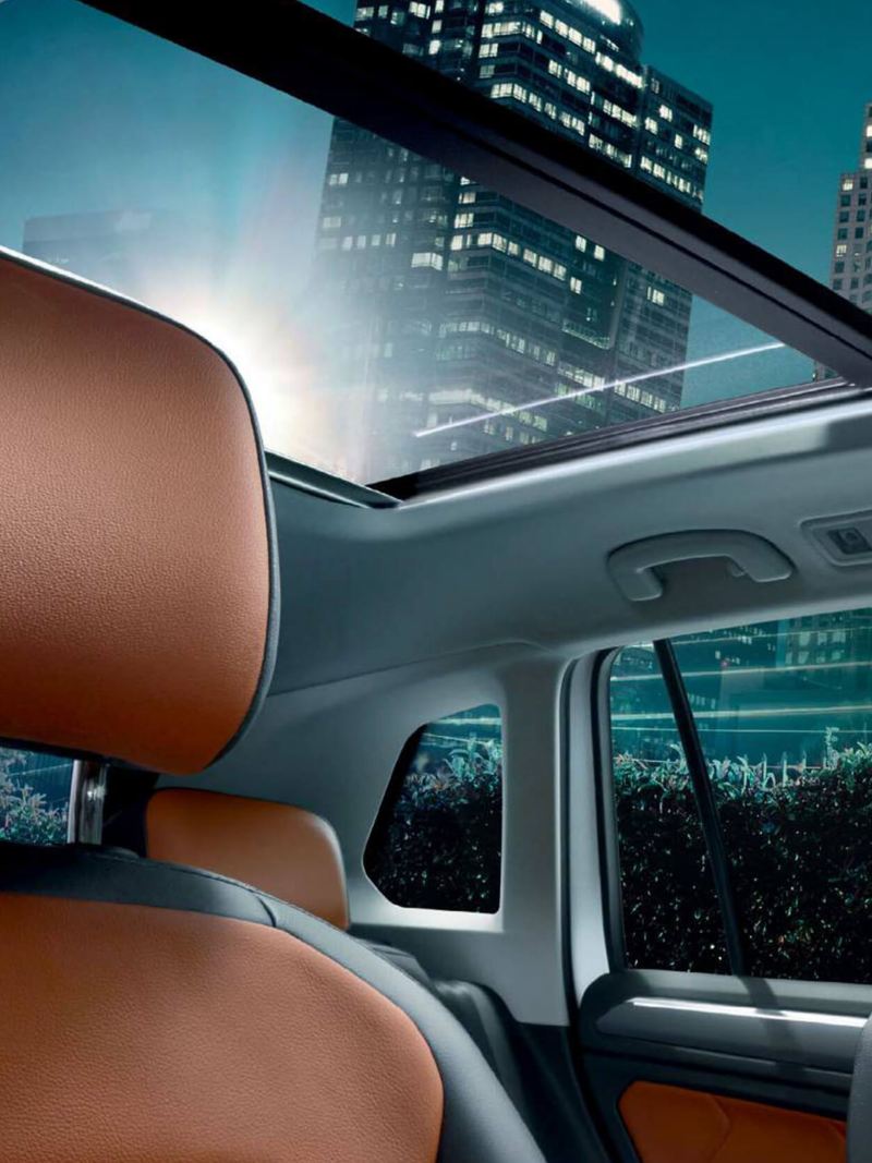 Interior shot of a Volkswagen Tiguan seats and sunroof, skyscrapers in the background.