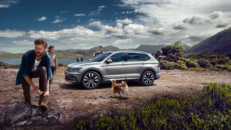 A group of people standing near a parked silver-coloured Tiguan Allspace 