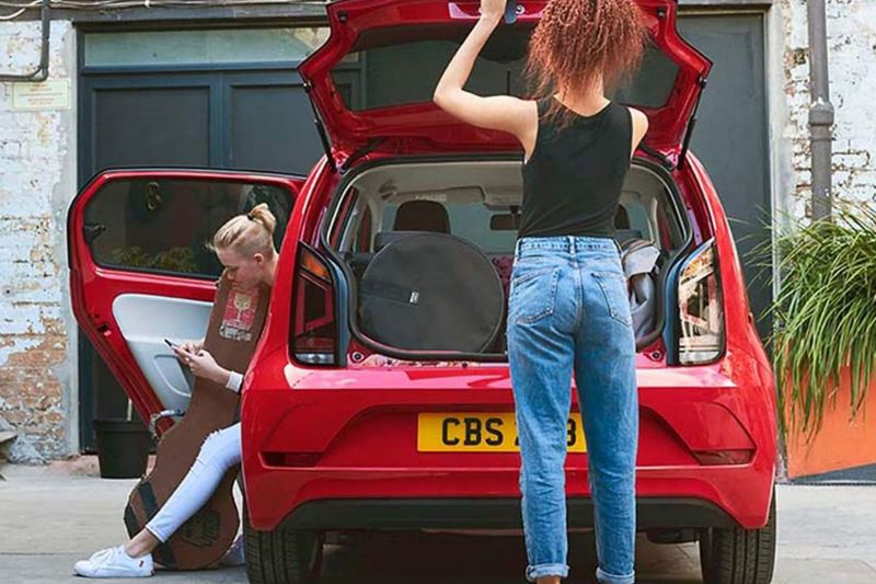 Rear shot of two ladies around a red Volkswagen up!