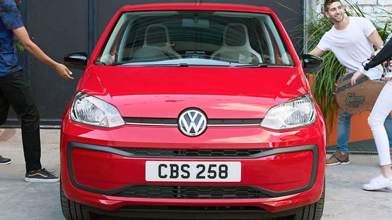 A group of friends getting into a red Volkswagen up!