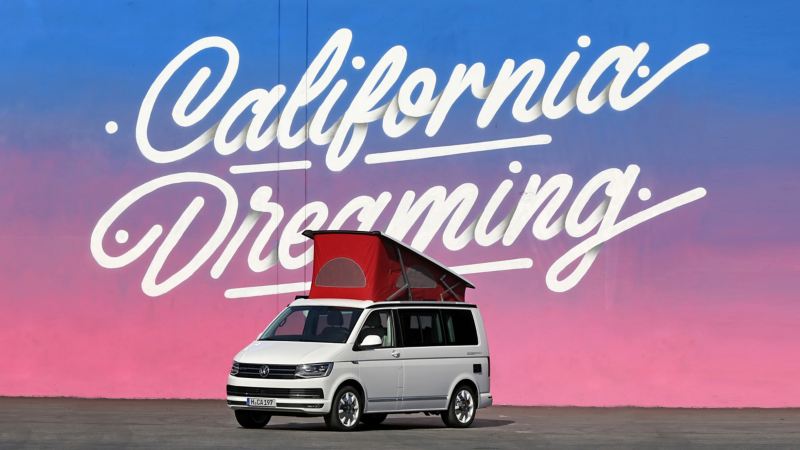 Ein Volkswagen Nutzfahrzeuge California mit Hochdach steht vor dem illustrierten Schriftzug „California Dreaming“.