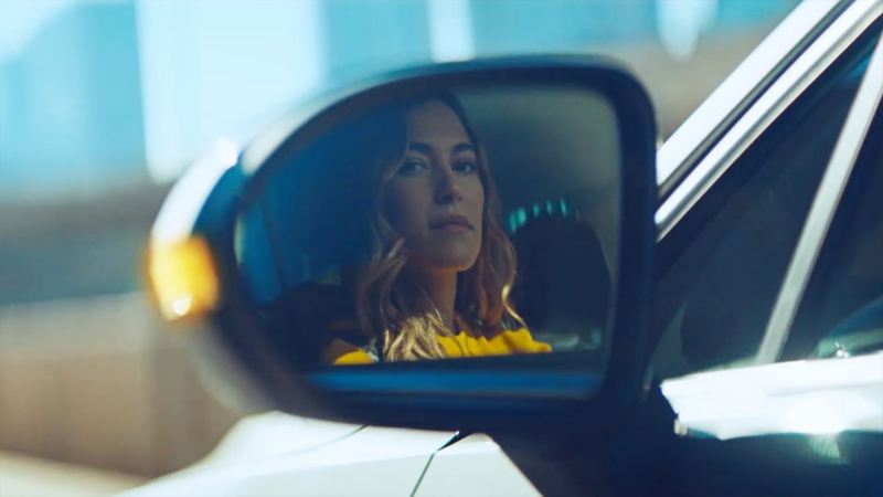 Eine Frau sitz im Auto und schaut in den Rückspiegel