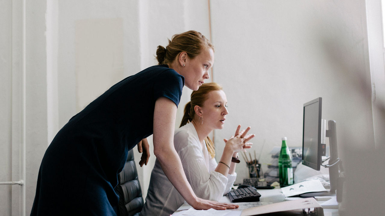 Two women working in an office in front of a computer