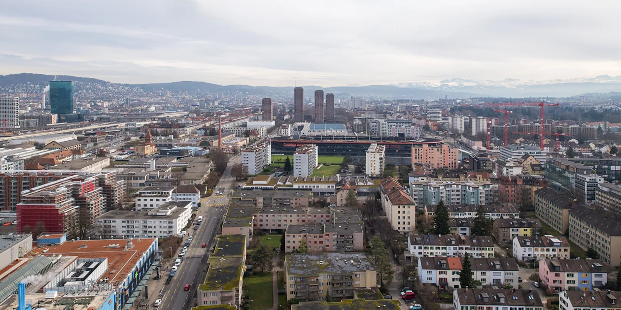 Das Titelbild der Online-Magazins der Stadtentwicklung Zürich: Ein Blick von oben auf die Stadt Richtung See, die vier Hardau-Hochhäuser überragen alle anderen Häuser.  