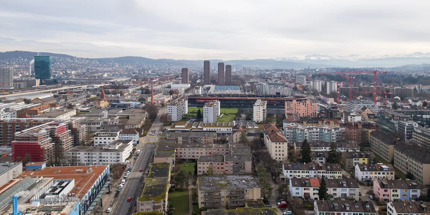 Das Titelbild der Online-Magazins der Stadtentwicklung Zürich: Ein Blick von oben auf die Stadt Richtung See, die vier Hardau-Hochhäuser überragen alle anderen Häuser.  