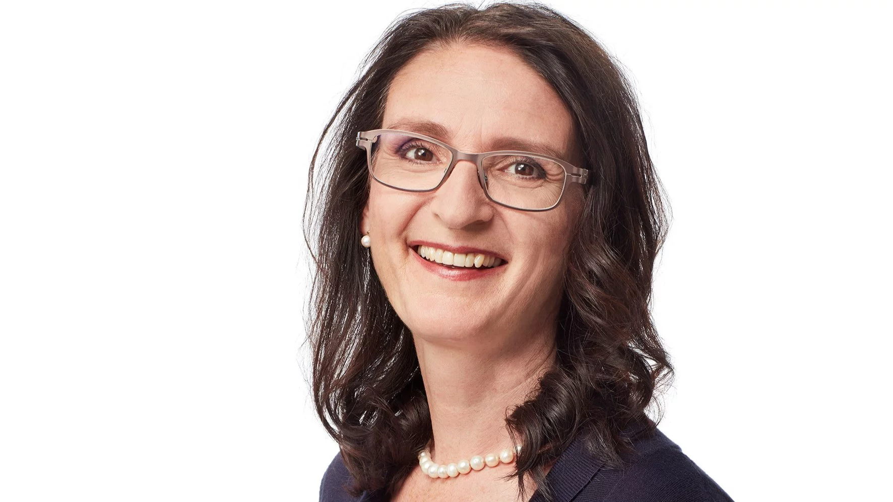 Das Porträt von Claudia Hollenstein, eine Frau mittleren Alters mit Brille lacht freundlich in die Kamera.