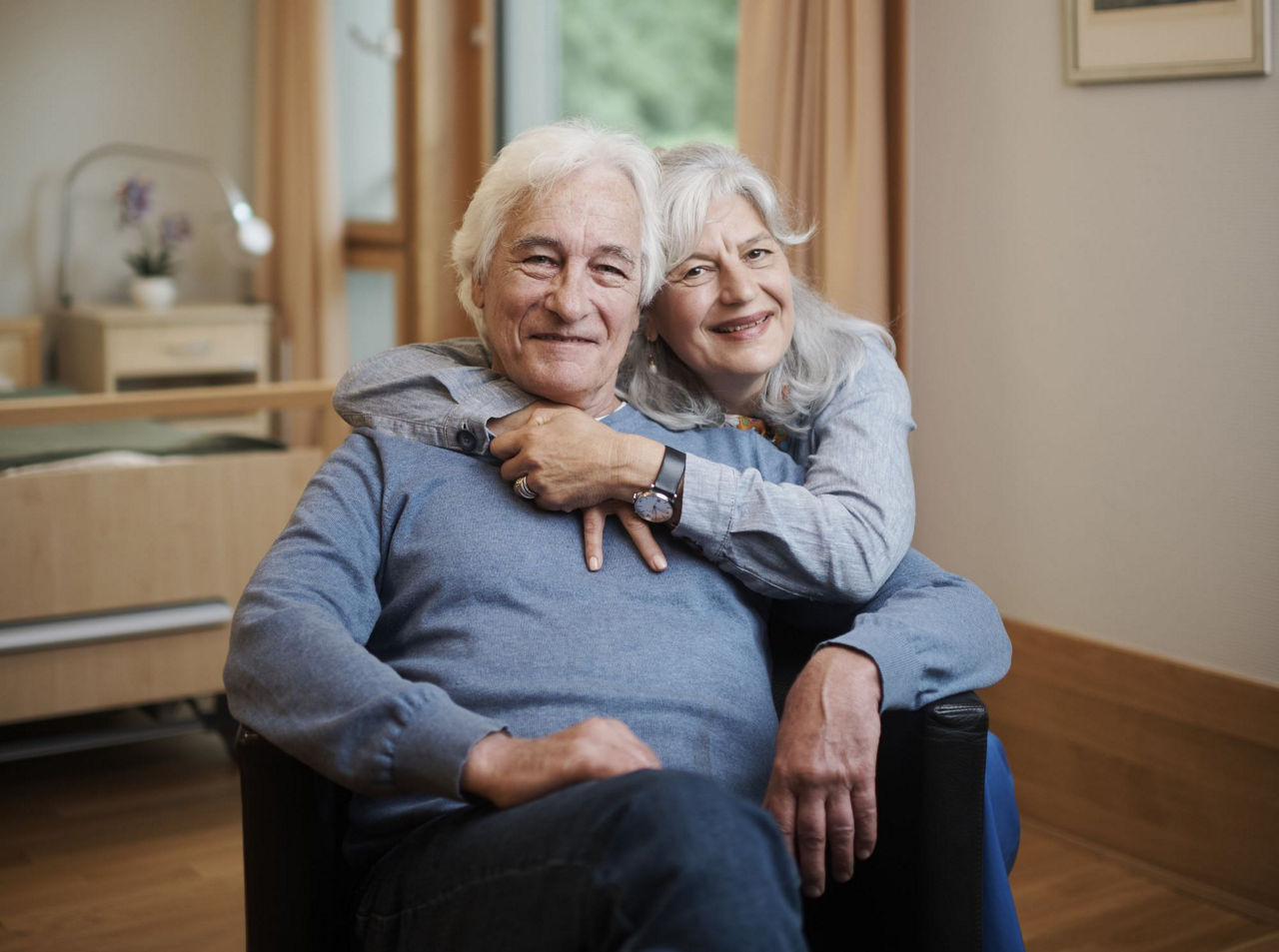 Ein Mann mit Demenz wird von einer Frau umarmt