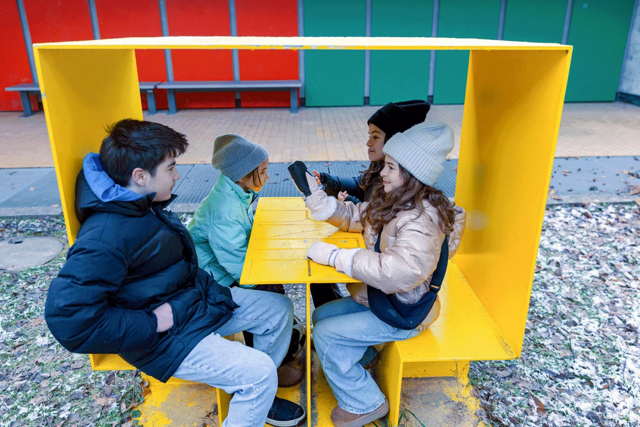 Kinder sprechen zusammen in einem Spiel-Häuschen in der Schule.