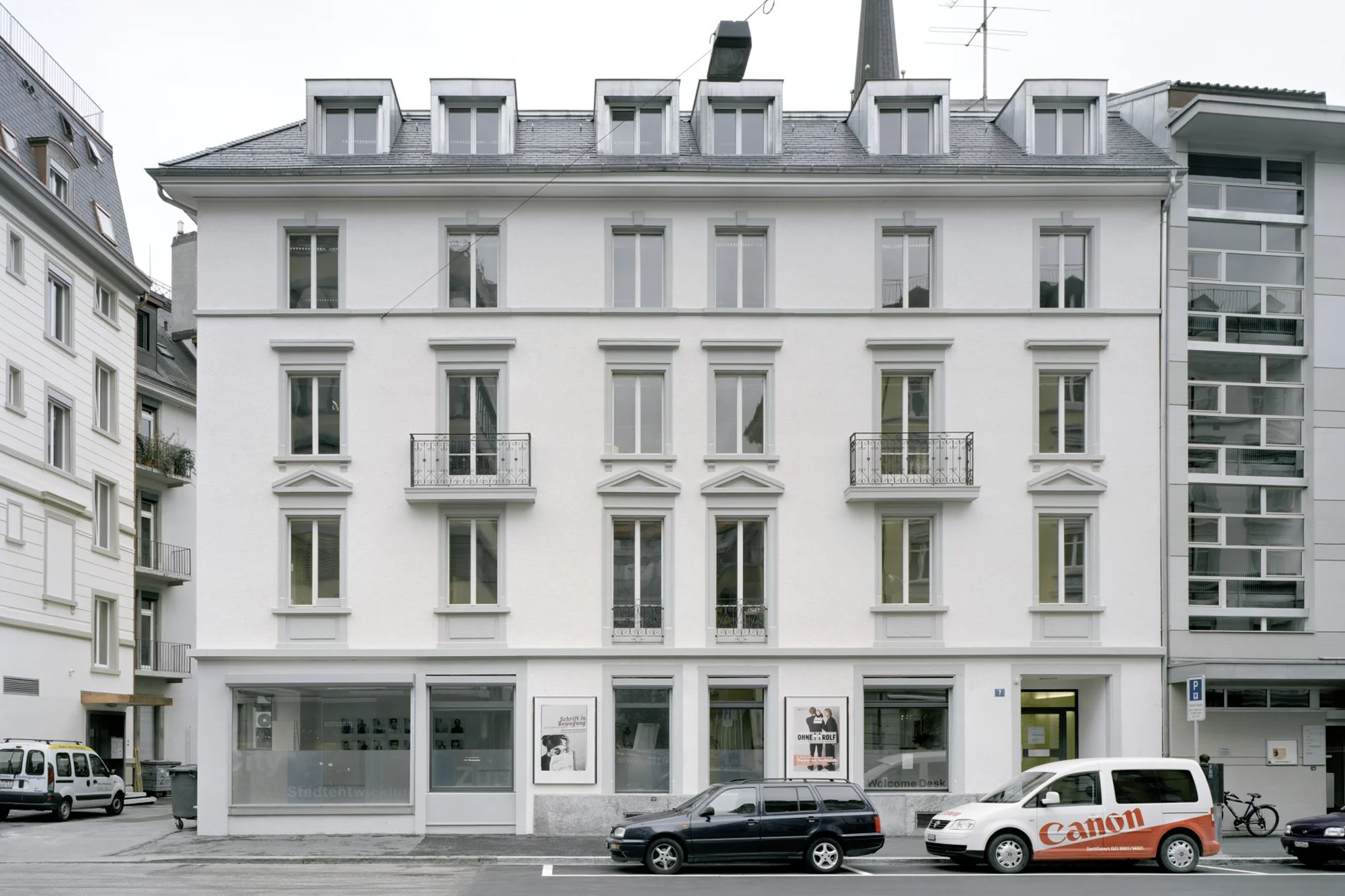 Aussenansicht auf die Fassade der Liegenschaft an der Bäckerstrasse 7 mit geparkten Autos im Vordergrund.