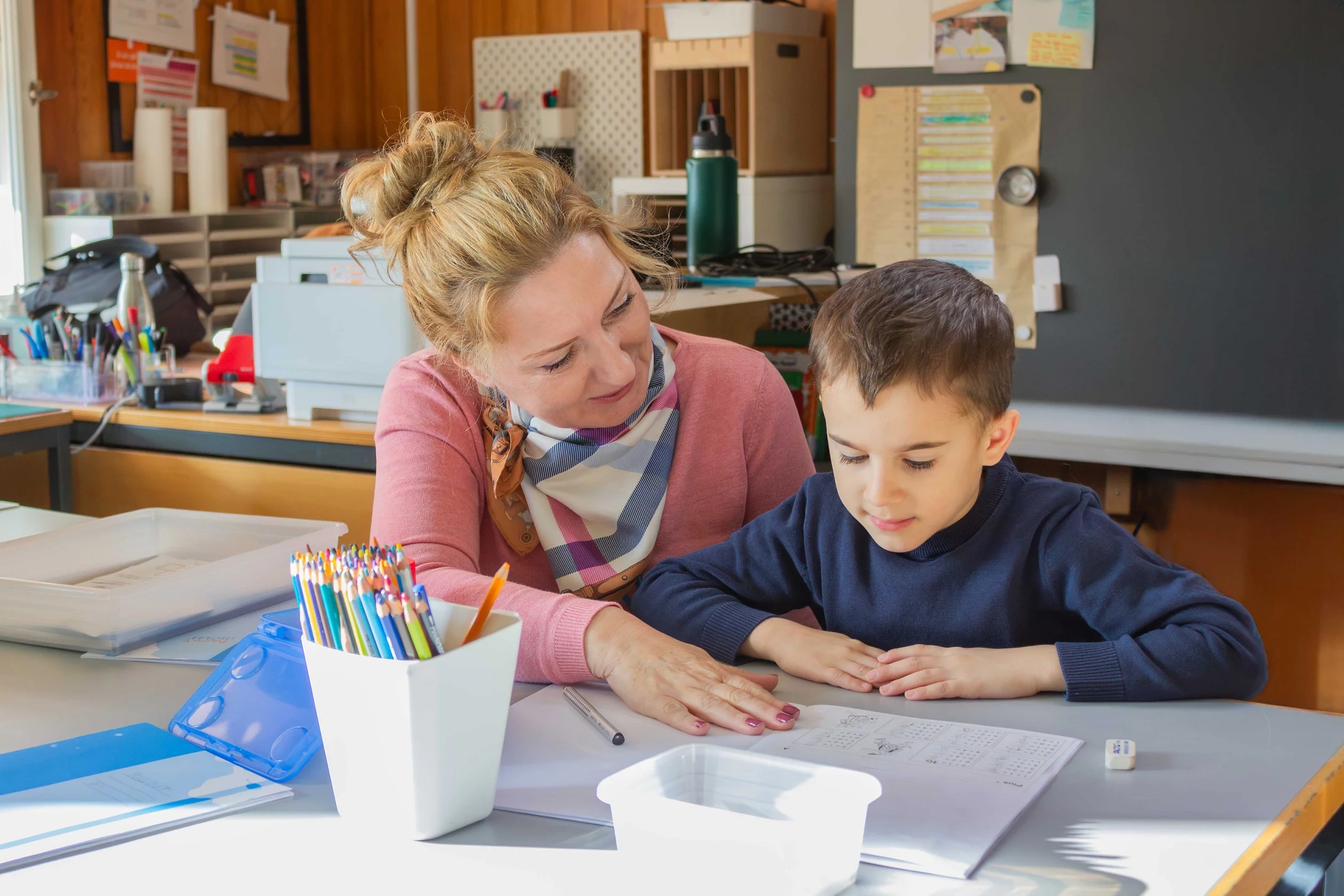 Eine Lehrperson unterstützt einen Schüler aufmerksam.